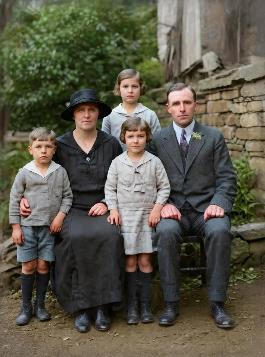 The same family of five restored and colorized, posed in front of a stone wall